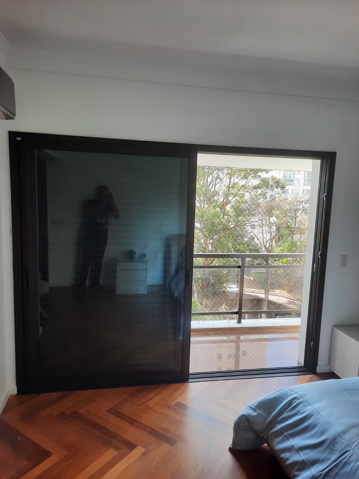 Fechamento de sacada concluído com porta de correr em vidro e vista para varanda.